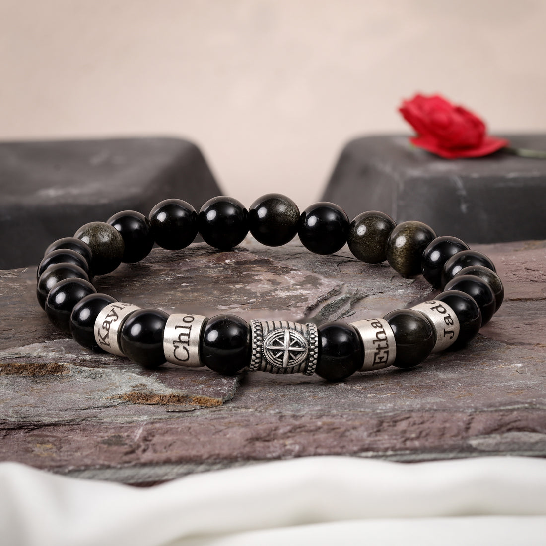 Personalized obsidian bracelet featuring silver compass charm and custom engraved names