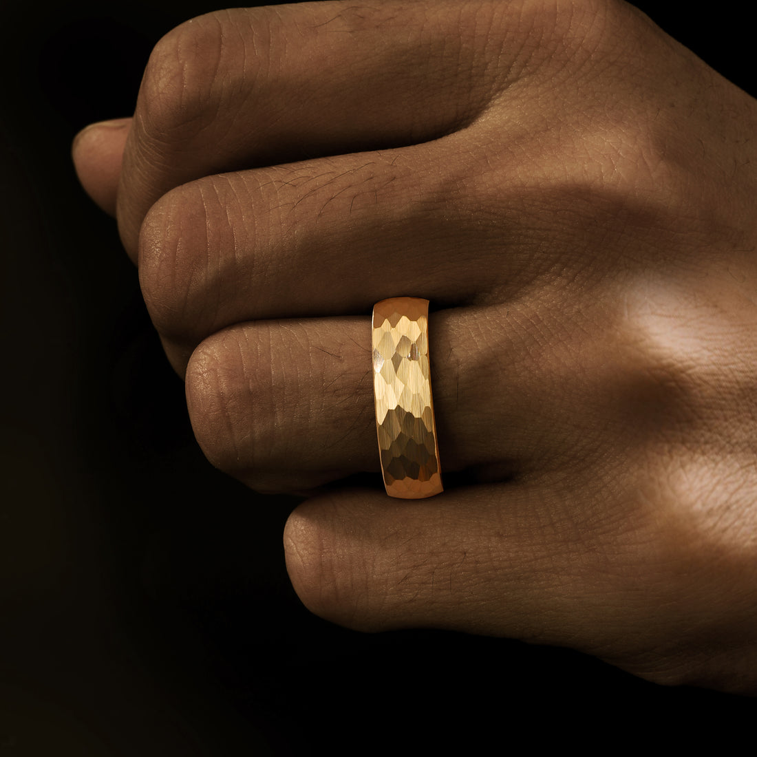 Handcrafted hammered gold wedding band for men showcasing a unique textured finish.