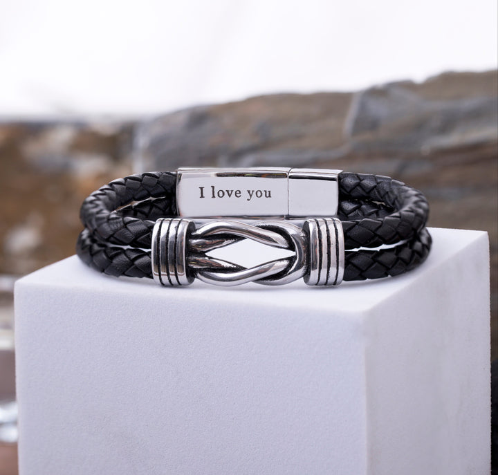 Close-up of a leather bracelet with an infinity charm, highlighting the detailed custom engraving inside the secure clasp