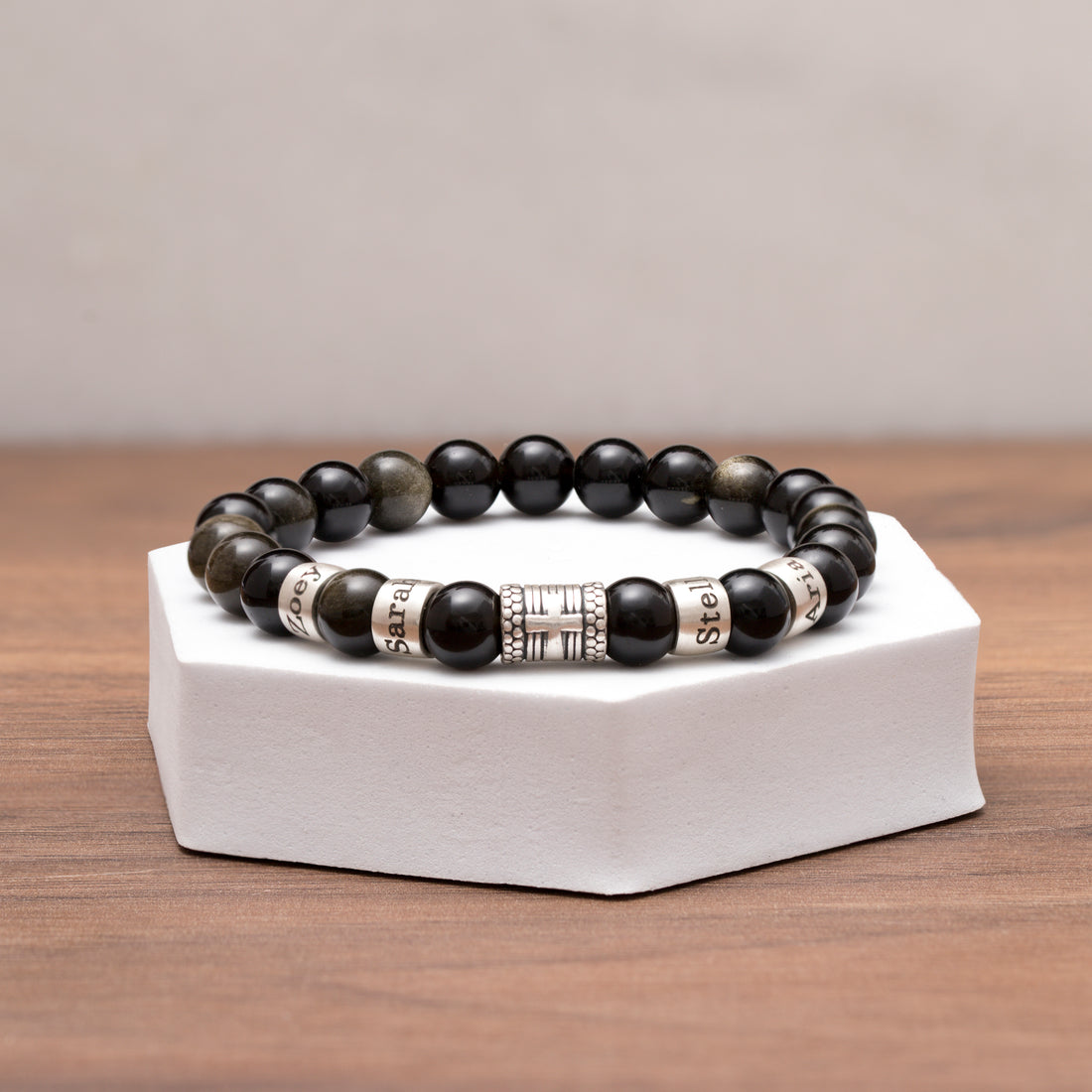 Black obsidian bead bracelet featuring engraved names and a silver cross charm, perfect for a personal and meaningful gift