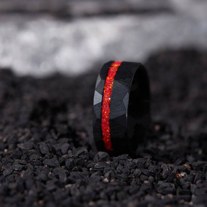 Close-up of a red opal ring for men, crafted in black tungsten with a hammered texture, showcasing the vibrant hues of the opal.